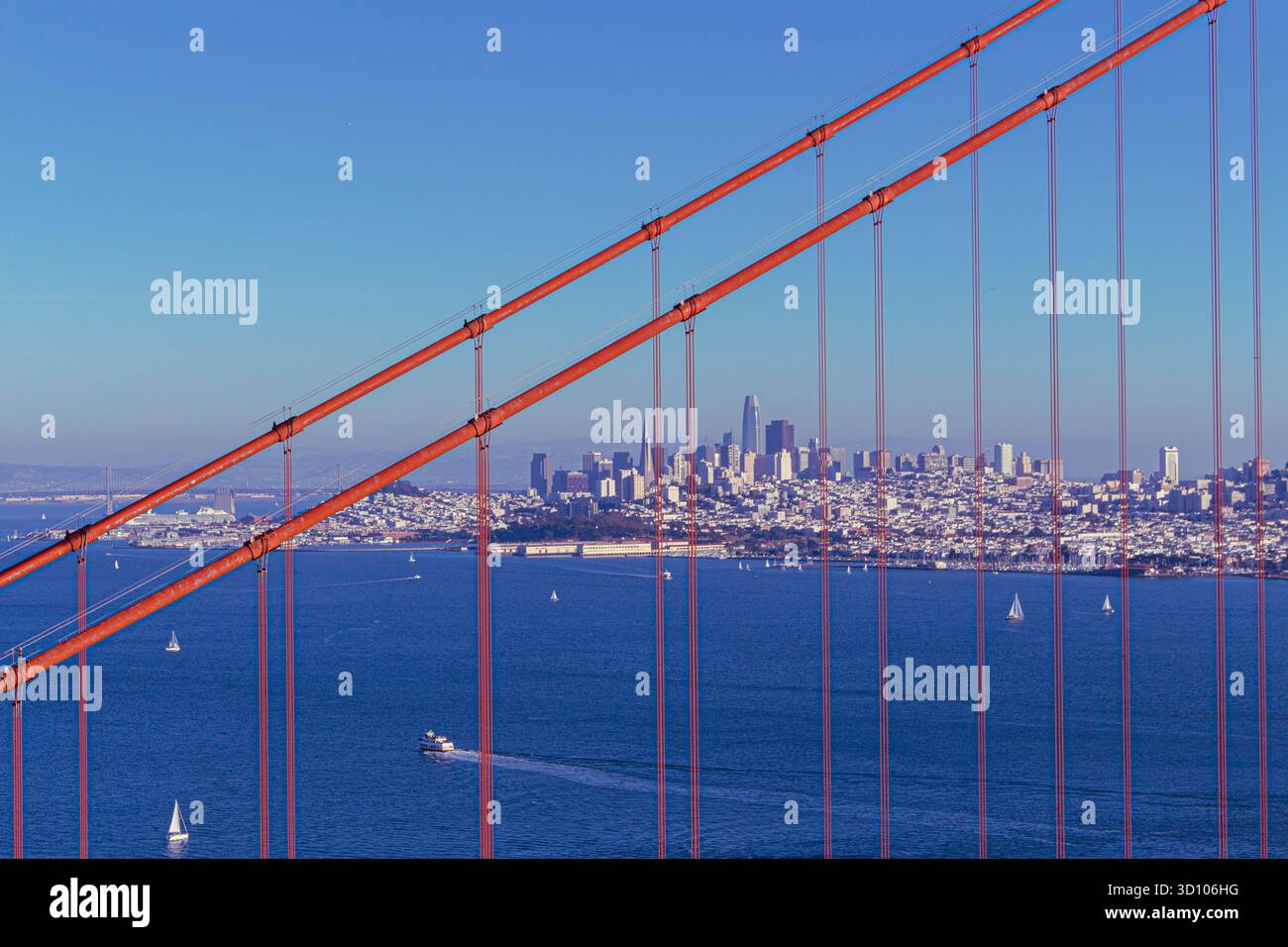 Golden Gate Bridge mit der Skyline von San Francisco in der Ferne – ikonisches Gebäude aus rotem Stahl, das die moderne Architektur der Stadt unter einem klaren Himmel umrahmt Stockfoto