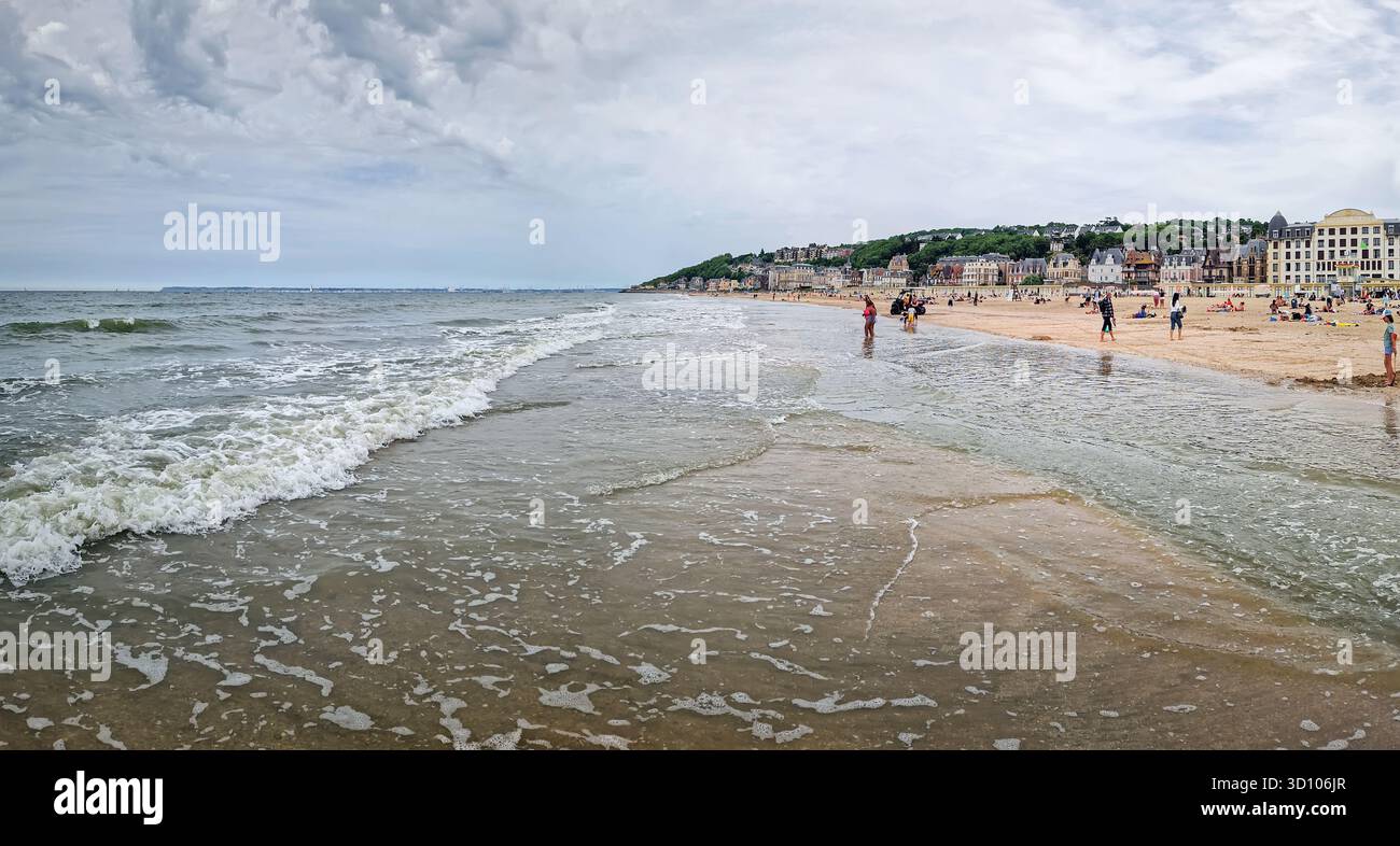 Trouville-sur-Mer, Normandie, Frankreich - 31. Mai 2025: Panoramablick auf den breiten Sandstrand und das Meer unter bewölktem Himmel mit dem bezaubernden Frenc Stockfoto