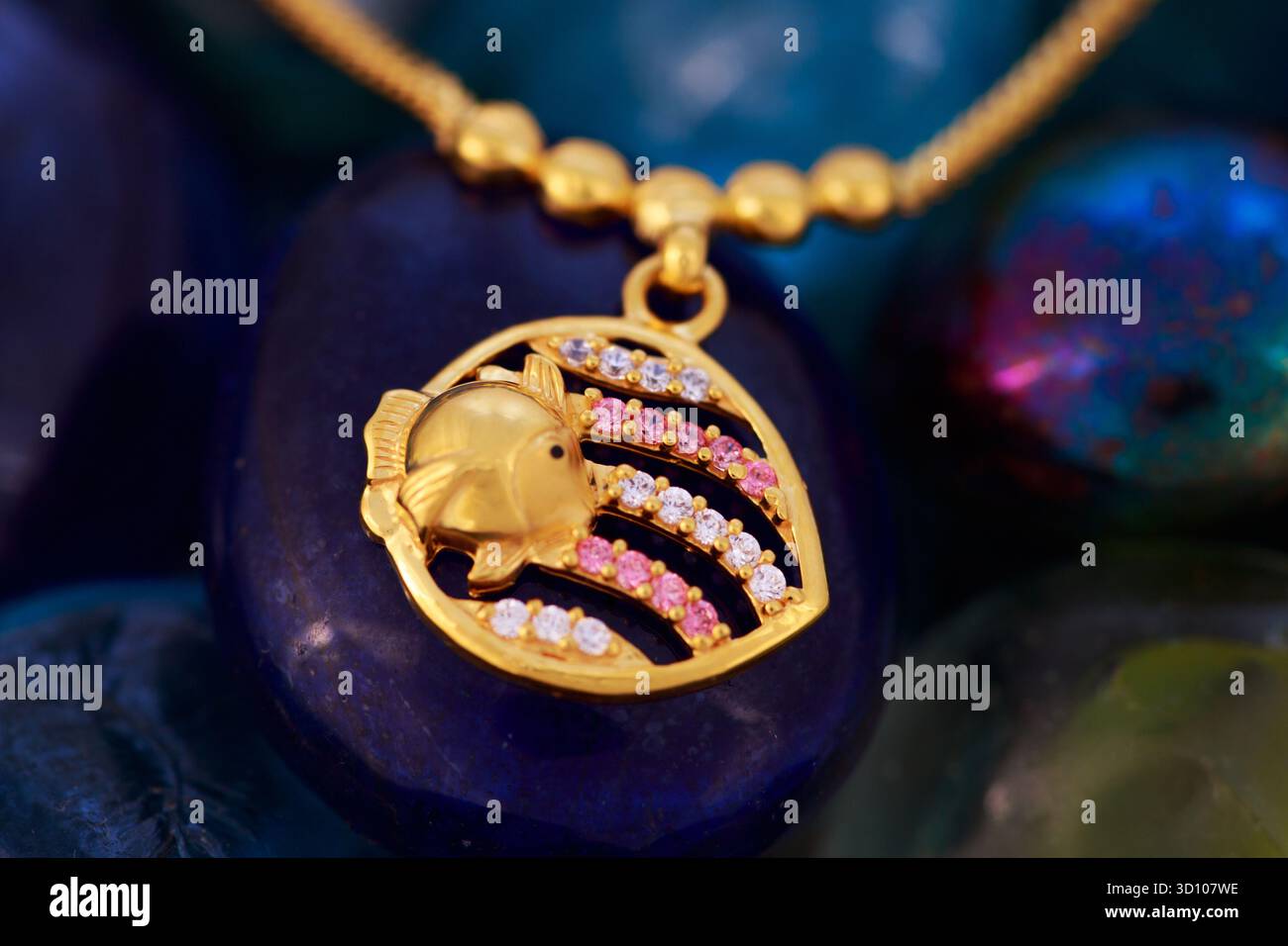 Gold Dollar und Kettenschmuck für Kinder – traditionelle indische Kinder Gold Ornament Nahaufnahme auf farbigem Steinhintergrund Stockfoto