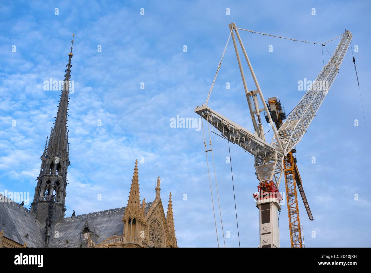 Letzte Etappe des Wiederaufbaus der Kathedrale Notre-Dame von Paris, Teil des Gebäudes mit Kirchturm und Dach und Kranboom gegen blauen Himmel. Renovierung Stockfoto