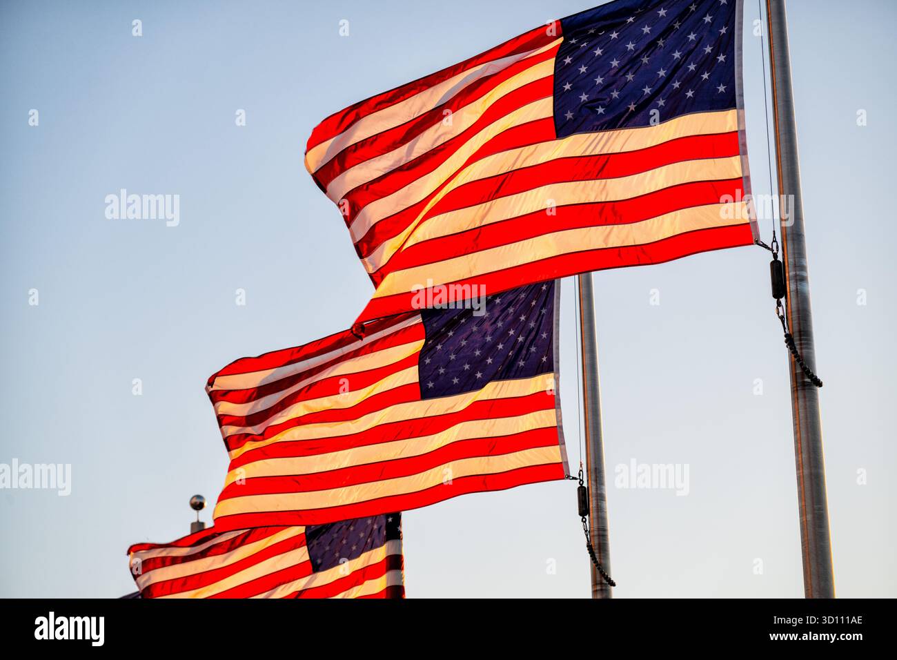 Amerikanische Flaggen im Golden Hour Light Washington DC // WASHINGTON DC – amerikanische Flaggen fliegen in der Nähe des Washington Monuments, beleuchtet durch goldenes Sonnenlicht am späten Nachmittag, nur wenige Minuten vor Sonnenuntergang. Dieser legendäre Obelisk an der National Mall erinnert an George Washington, den ersten US-Präsidenten. Das aus Marmor, Granit und Blausteingneis erbaute Denkmal wurde 1884 fertiggestellt. Es ist das höchste Steinbauwerk der Welt und der höchste Obelisk mit einer Höhe von 169,046 Metern (554 Fuß 7 11/32 Zoll). Diese Flaggen sind Teil der patriotischen Ausstellung, die dieses prominente nationale Wahrzeichen umgibt. Stockfoto