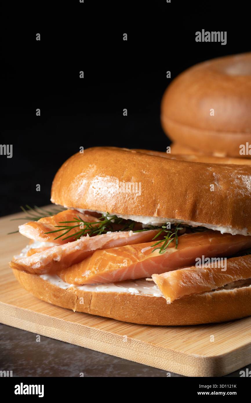 Ein Sandwich mit Lachs und Dill auf einem Brötchen. Das Sandwich sitzt auf einem hölzernen Schneidebrett Stockfoto