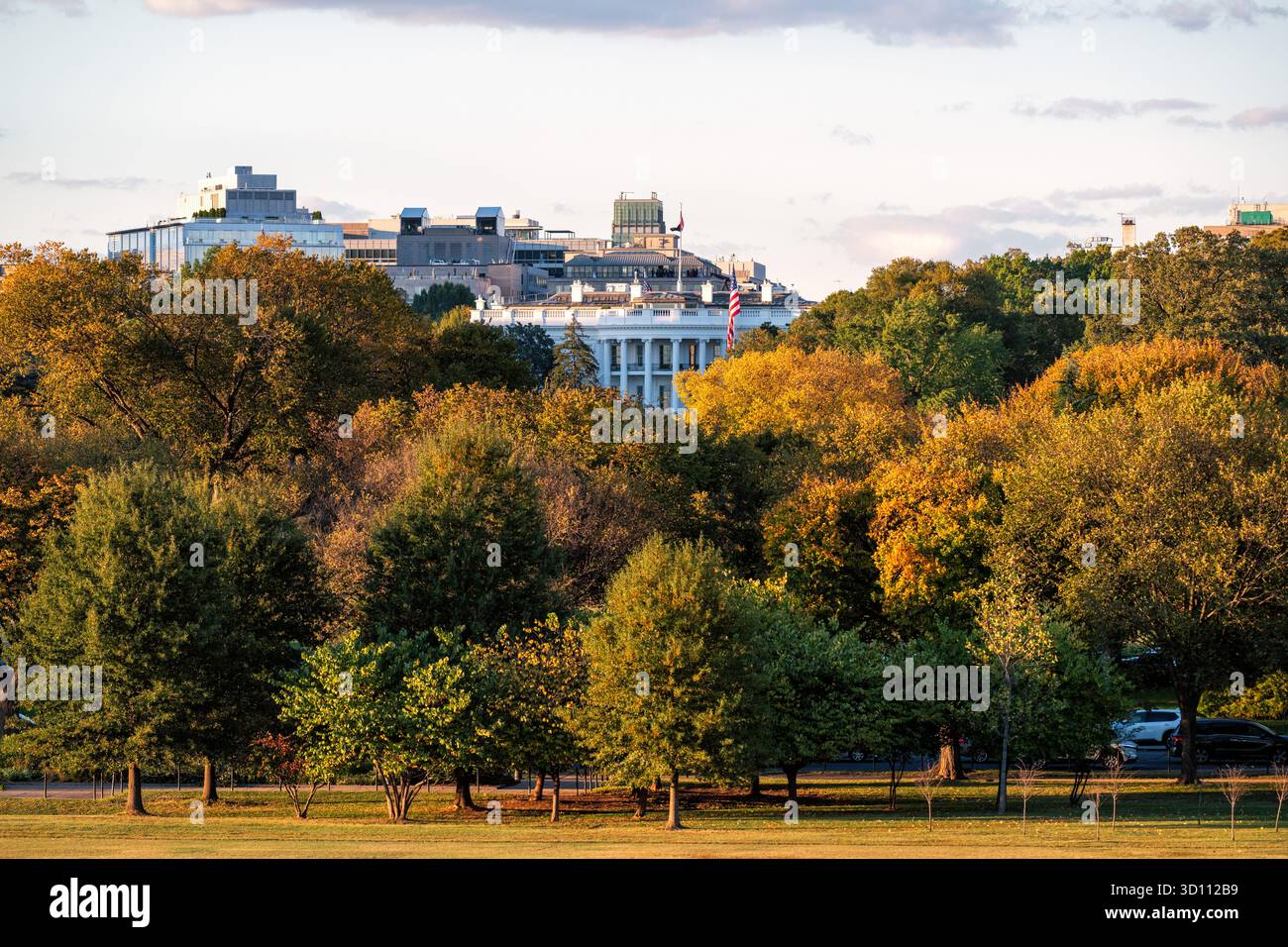 Weißes Haus durch Bäume Washington DC USA // WASHINGTON DC – das Weiße Haus ist durch Herbstbäume sichtbar, wie es von der Basis des Washington Monuments aus bei spätem Sonnenlicht am Nachmittag gesehen wird. Dieses ikonische Gebäude befindet sich an der 1600 Pennsylvania Avenue NW und ist der offizielle Wohnsitz und Hauptarbeitsplatz des Präsidenten der Vereinigten Staaten. Der Blick blickt nach Norden über den Ellipse, einen 52 Hektar großen Park, der Teil des President's Park ist. Das von James Hoban entworfene Weiße Haus wurde 1800 fertiggestellt. Stockfoto