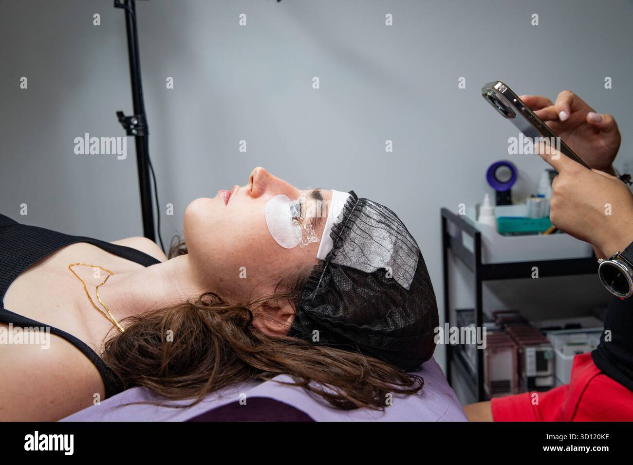 Wimpernpflege im Salon: Nahaufnahme einer Frau mit geschlossenen Augen. Ein Spezialist und ein Kunde im Salon Stockfoto