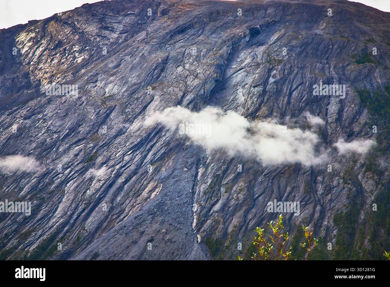 Wolken treiben über die zerklüftete Bergwand mit Vegetation in der kanadischen Wildnis Stockfoto