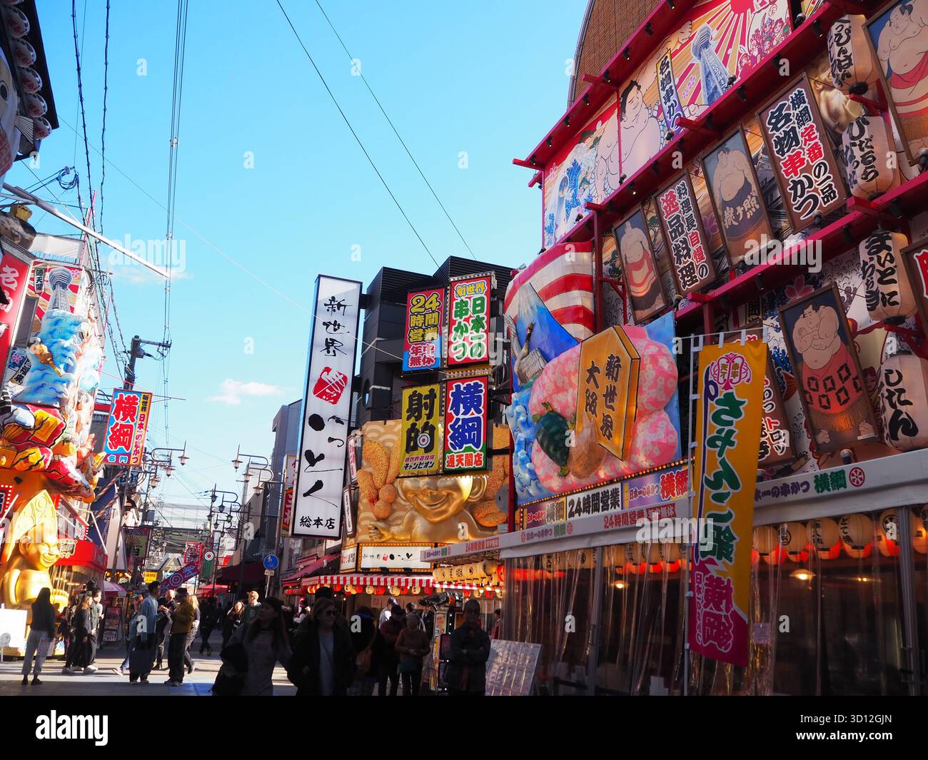 Shinsekai Straße mit farbenfrohen Restaurantschildern und lebhaften Geschäften in der Nähe von Tsutenkaku im Retro-Unterhaltungsviertel Osakas Stockfoto