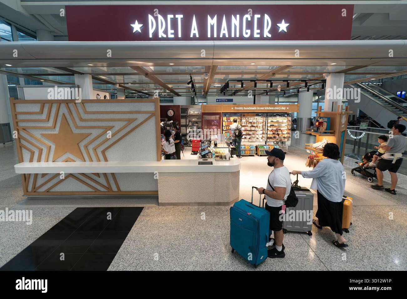 Hongkong - 20. September 2025: Ein Reisender steht mit Gepäck in der Nähe des Pret A Manger Sandwiches und Coffee Shop, einem beliebten Einzelhandels- und Gastronomiegeschäft Stockfoto