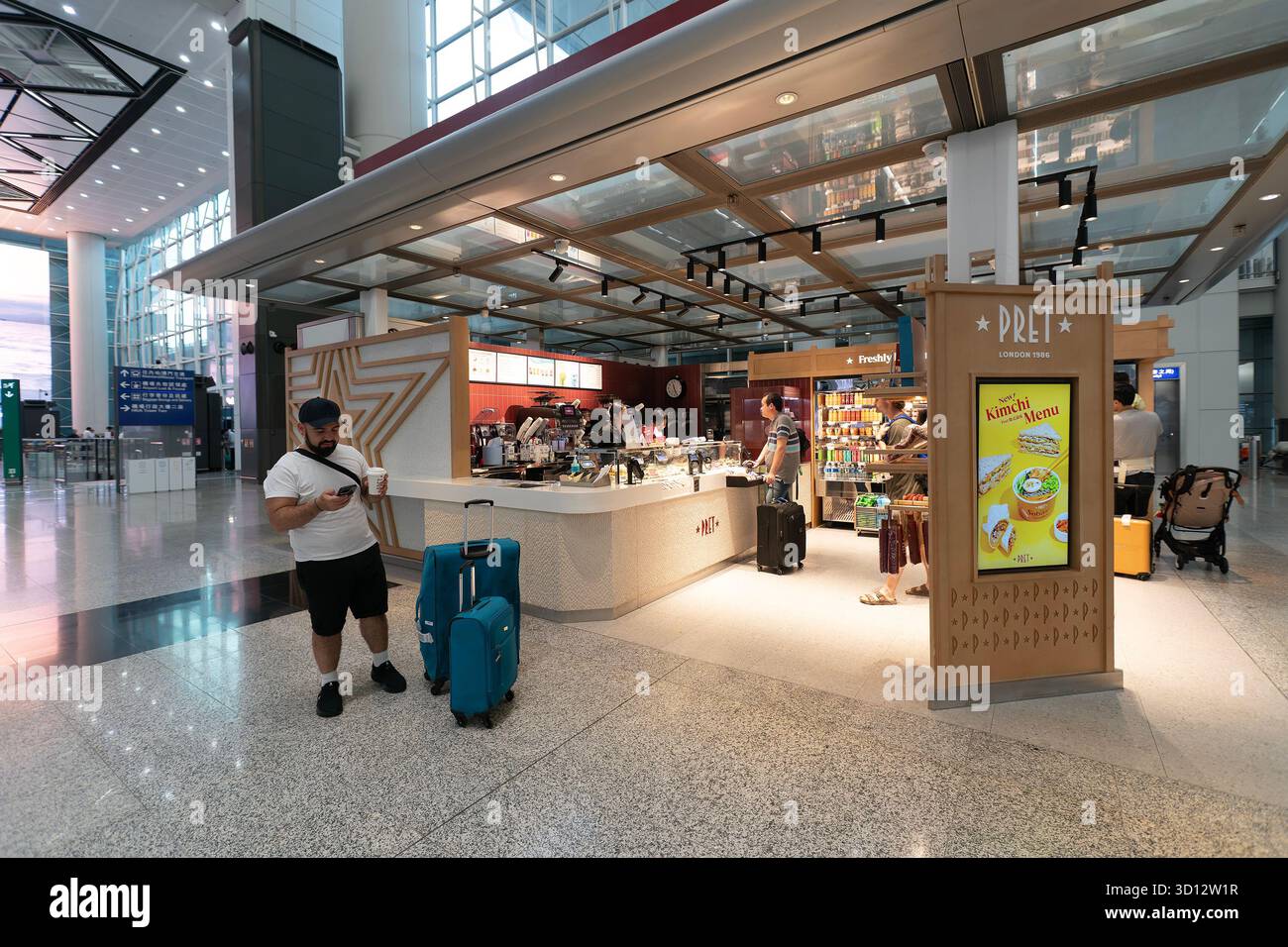 Hongkong - 20. September 2025: Ein Reisender steht mit Gepäck in der Nähe des Pret A Manger Sandwiches und Coffee Shop, einem beliebten Einzelhandels- und Gastronomiegeschäft Stockfoto
