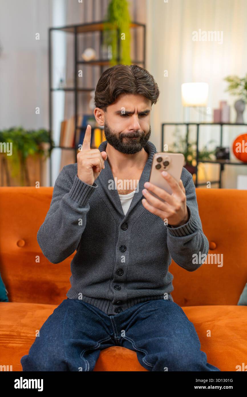 Indischer Mann zu Hause spielt Handy-Casino verliert Wette Seufzer hält Kopf reibt Stirn, keine Geste. Arabianer auf dem Sofa sieht Ergebnis traurig sagt nein mit Hand bestürzt Stimmung nach dem Verlust des Online-Glücksspiels Stockfoto