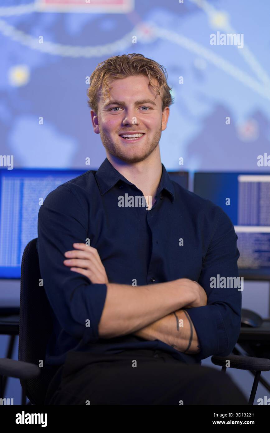 Selbstbewusster junger Fachmann im Kontrollraum mit technischem Hintergrund Stockfoto