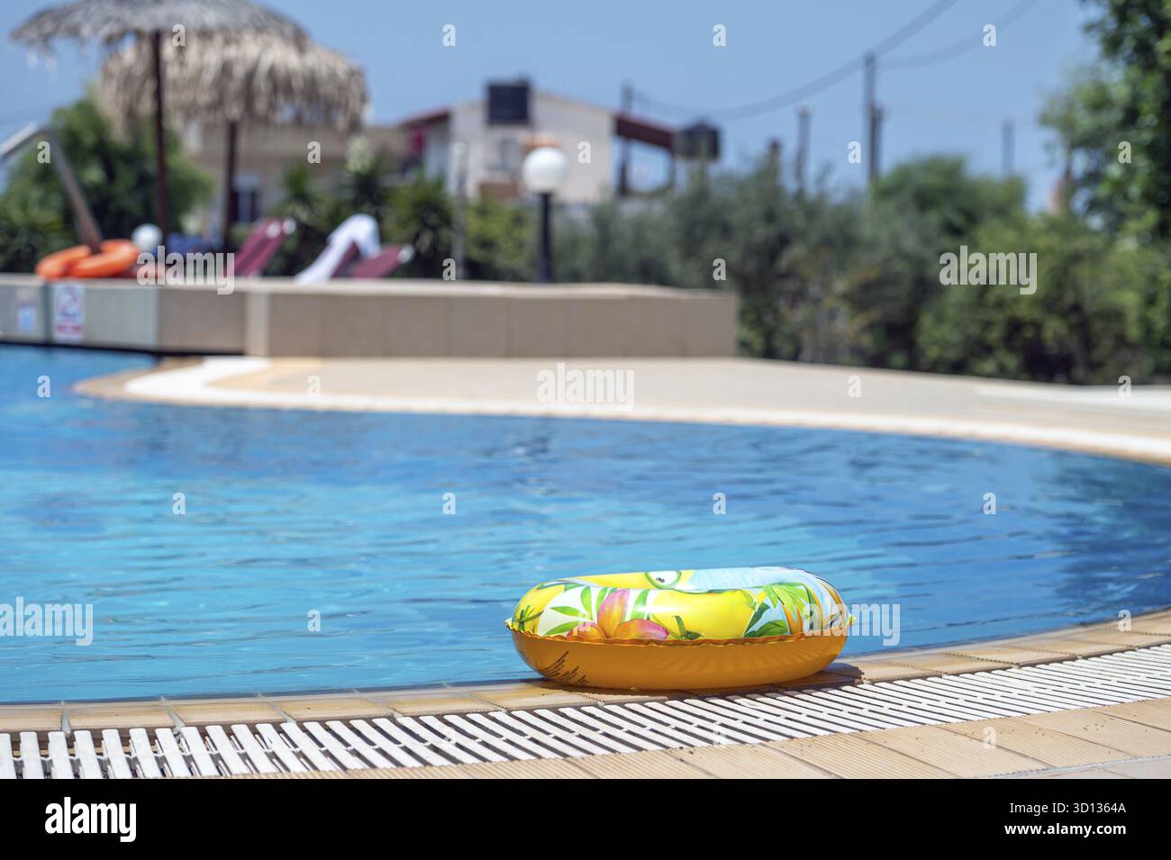 An einem hellen Sommertag schwingt ein farbenfroher Ring am Rand eines glitzernden Pools auf Kreta Stockfoto