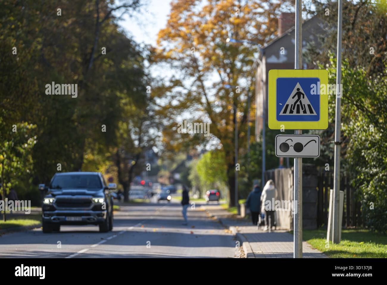 An einem sonnigen Herbsttag fließt der Verkehr an einer hellen Fußgängerüberquerung vorbei Stockfoto