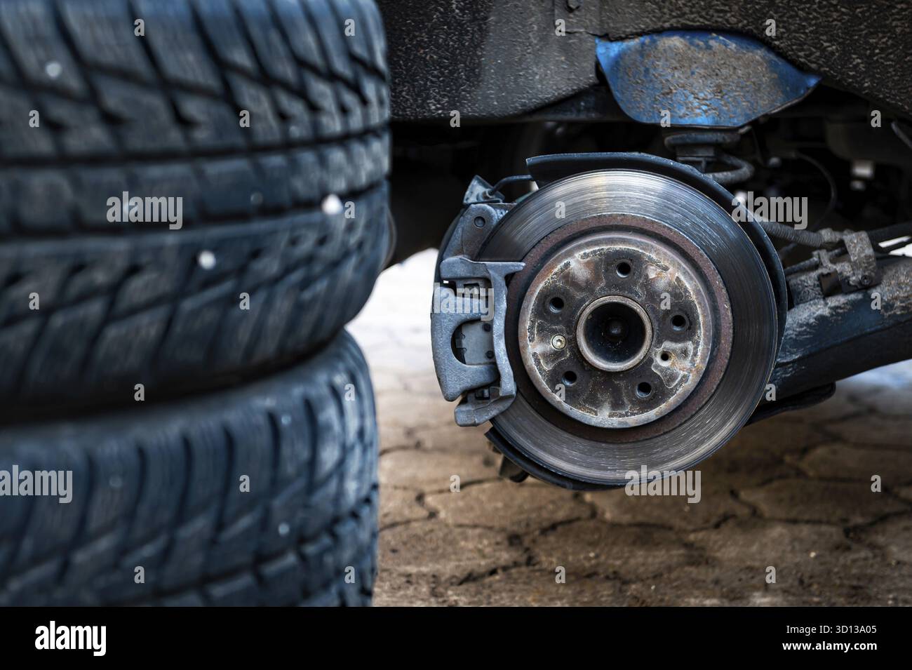 Winterreifen neben dem Auto, saisonales Reifenwechselkonzept, selektiver Fokus, Fokus auf das Auto, Nahaufnahme Stockfoto