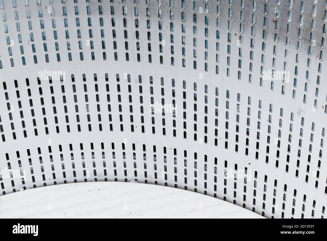 Perforiertes Blech mit industrieller Textur und gleichmäßigen Schlitzmustern, die einen abstrakten Hintergrund bilden Stockfoto