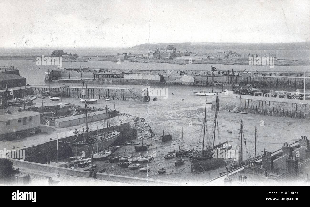 Schwarz-weiße Hafenansicht von St. Helier, Jersey, vom 10. August 1908, veröffentlicht von Léon & Lévy. Segelboote und kleine Schiffe gruppieren sich um hölzerne Piers und eine Schutzmauer. Gebäude am Wasser und Dächer säumen den Vordergrund, während eine ferne Küstenlinie und eine erhöhte Struktur, eine Burg, den Horizont ankern. Eine anschauliche Momentaufnahme der eduwardischen maritimen Infrastruktur. Von einer Originalpostkarte. Stockfoto