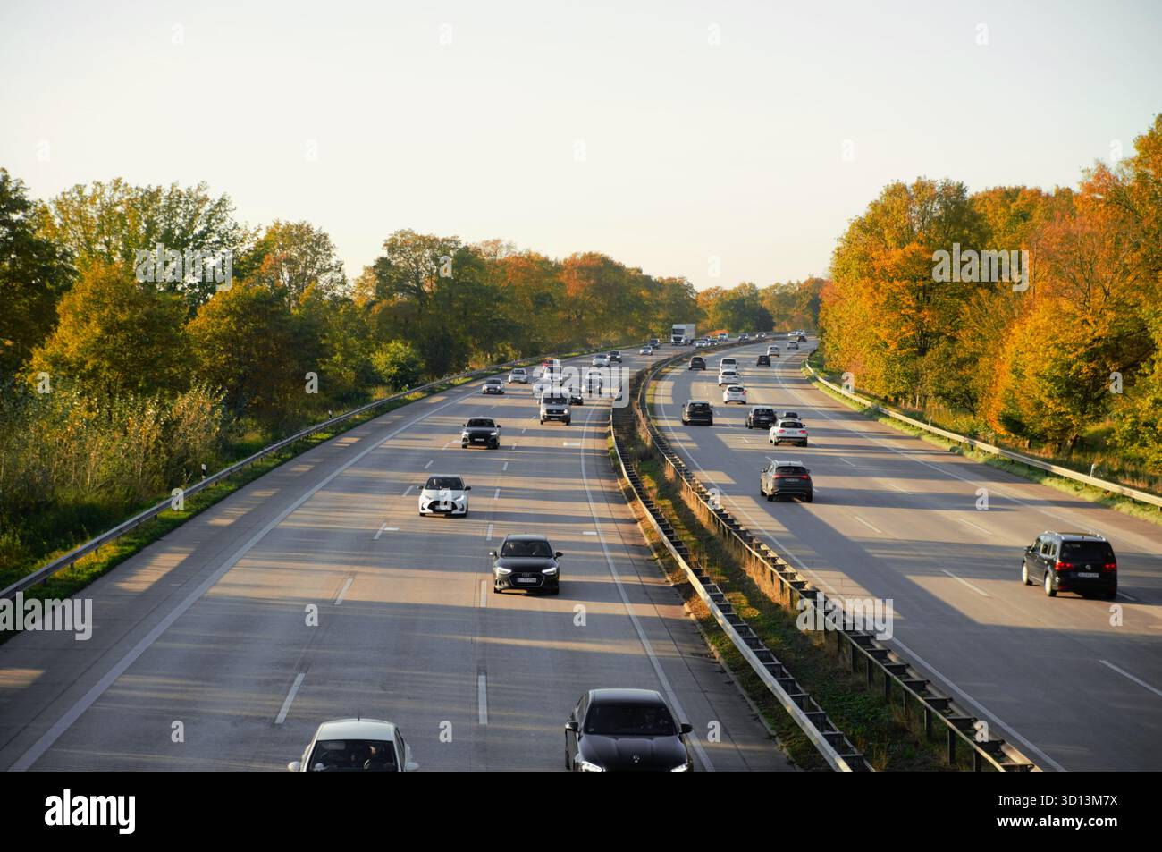 Blick auf die Herbstautobahn mit Autos im seitlichen Sonnenlicht Nahaufnahme selektiver Fokus Stockfoto