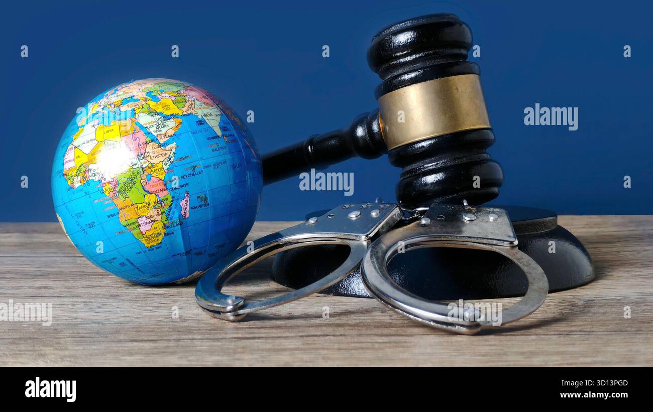Miniatur Weltkugel, Handschellen und Gavel symbolisieren internationales Recht und globale Gerechtigkeit Stockfoto