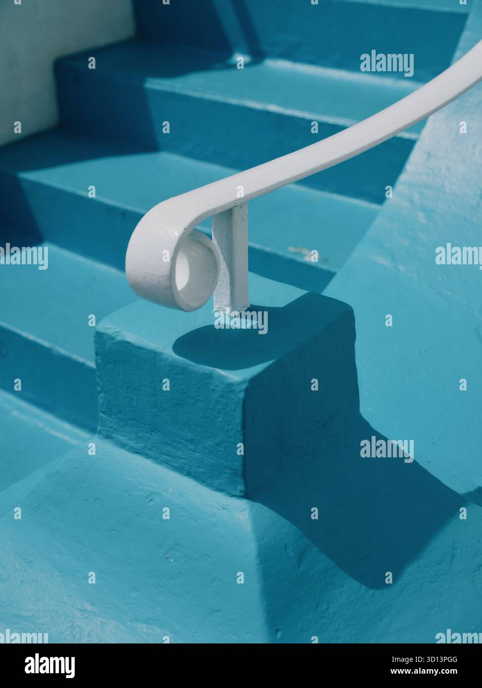 Ein weißer Handlauf und blau lackierte Stufen Stockfoto