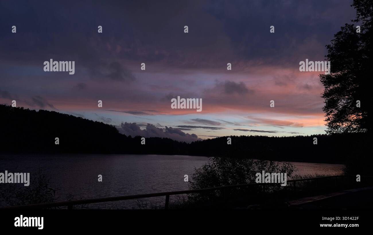 Sonnenuntergang über dem Zarasai-See, Litauen. Abendlicher Blick auf den Zarasai See bei Sonnenuntergang im Sommer, mit farbenfrohem Himmel und ruhigem Wasser, das das letzte Licht reflektiert. - Smartphone-aufgenommenes Stockfoto