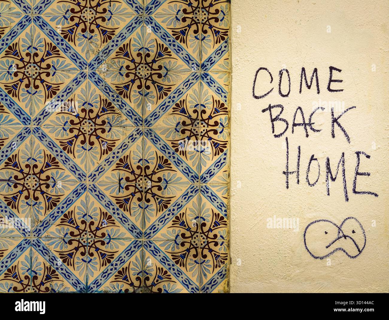 Lissabon, Portugal – traditionelle Azulejo-Wand mit handgeschriebener Graffiti-Botschaft „Come Back Home“ Stockfoto