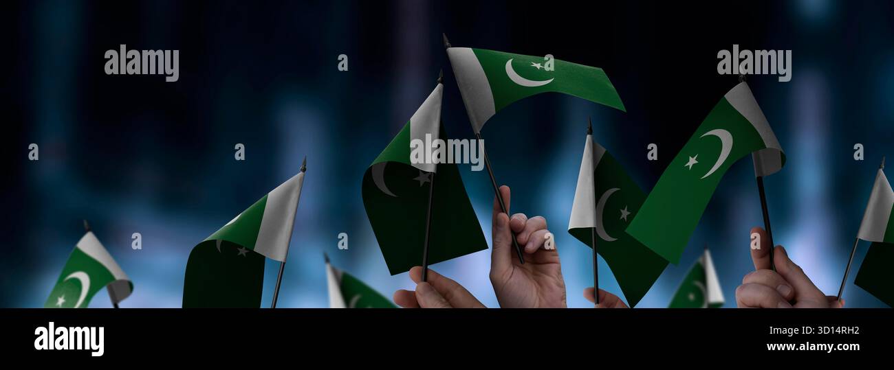 Pakistanische Flaggen in den Händen vor einem verschwommenen urbanen Hintergrund. Die Fotoillustration wurde ohne künstliche Intelligenz erstellt, nur mit Photoshop. Stockfoto