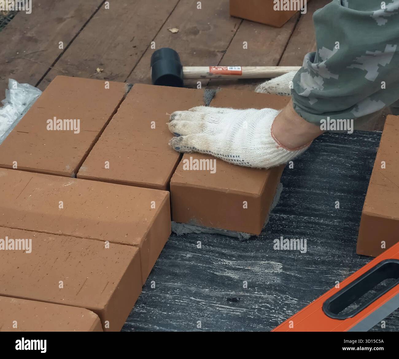 Ein Mann baut eine Mauer. Brick hat die Lösung aufgesetzt. Bau eines Backsteinhauses Stockfoto