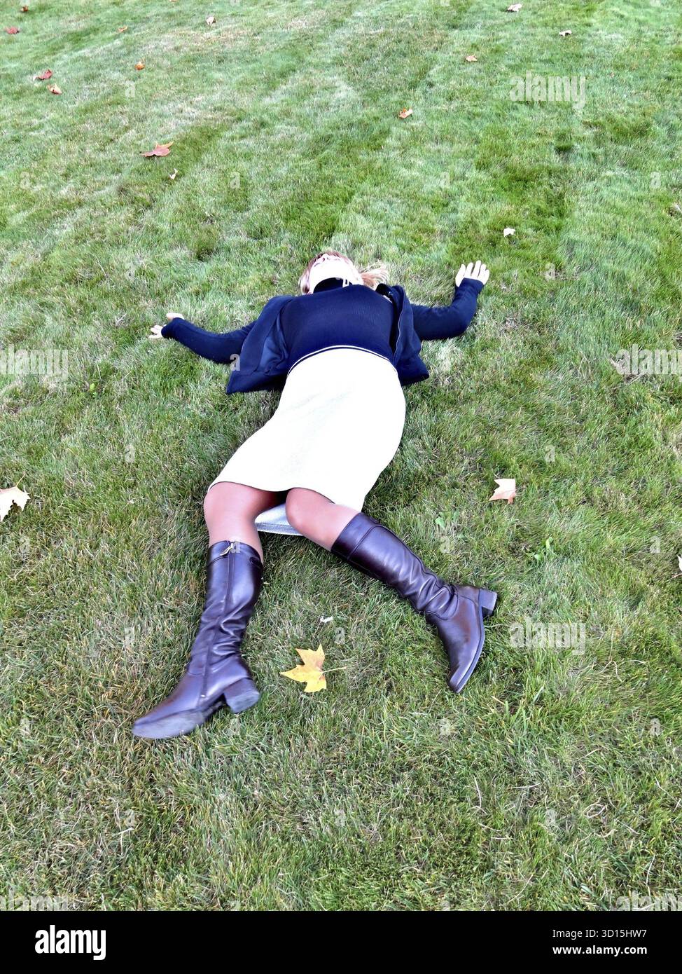 Blondes Mädchen in einem hellen Rock, das auf dem grünen Gras liegt Stockfoto