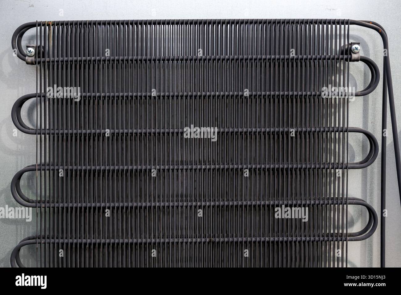 Metallgitter-Kondensatorspulen auf der Rückseite des Kühlschranks, die den industriellen Aufbau und die funktionalen Kühlsysteme zeigen, Nahaufnahme Stockfoto