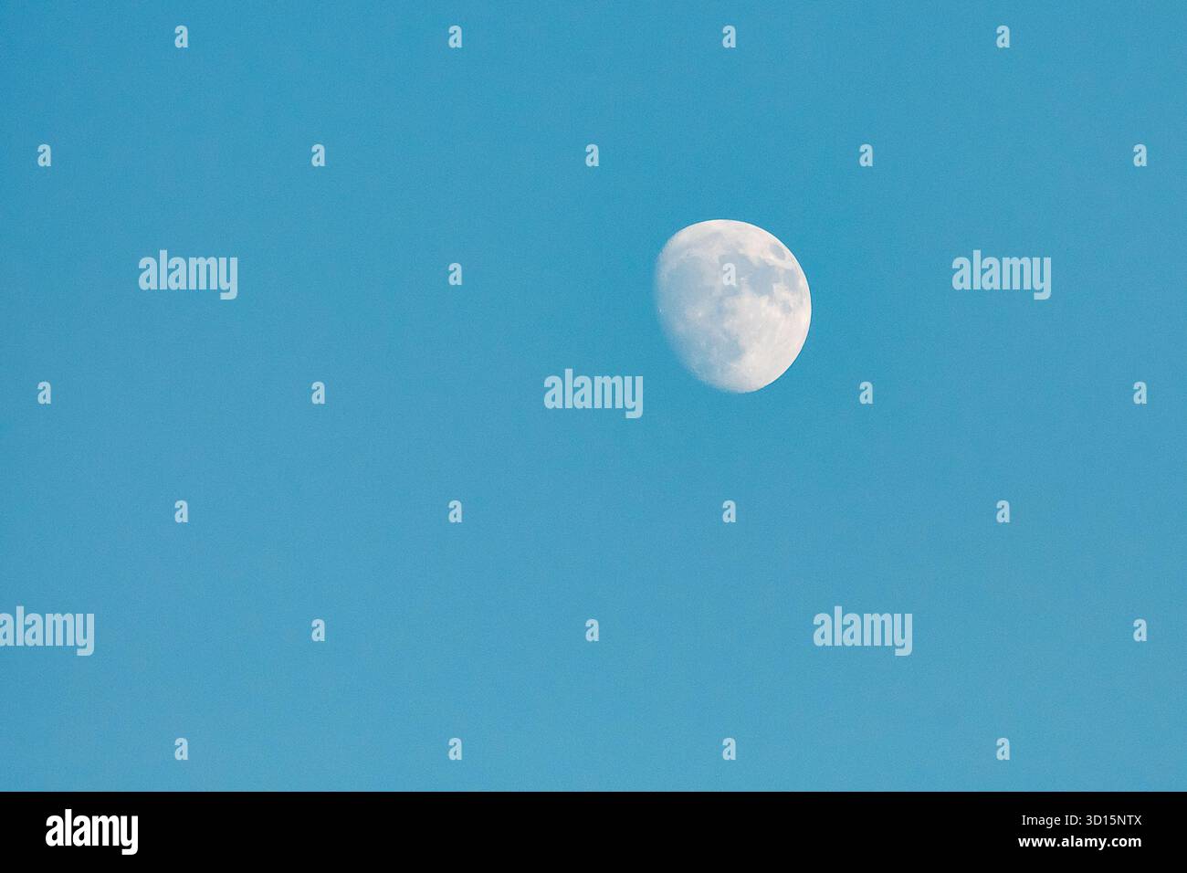 Ein abnehmender Mond scheint hell in einem klaren blauen Himmel und zeigt seine Schönheit tagsüber. Stockfoto