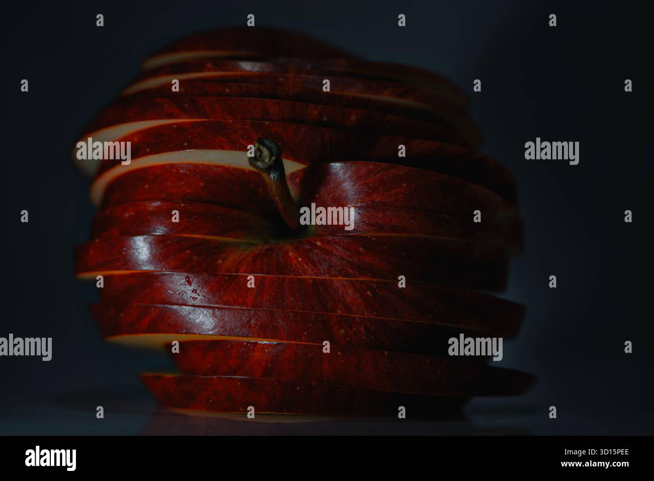 Knusprige, mehrschichtige Fruchtkomposition, Nahaufnahme glänzender Apfelscheiben unter dramatischem Licht Stockfoto