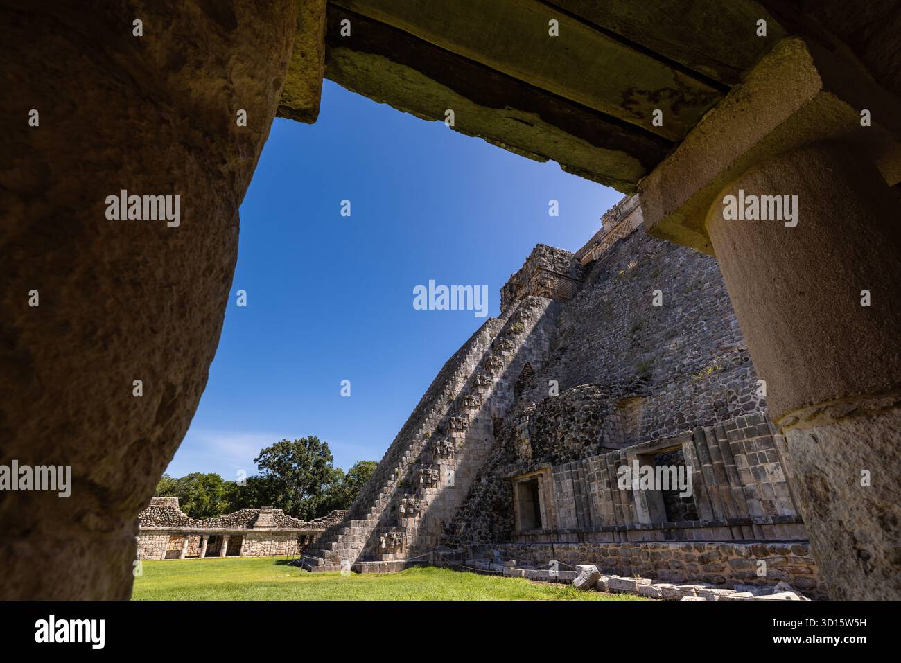 Blick auf die Pyramide des Magiers, eingerahmt von Ruinen aus Steinbögen in Uxmal, Yucatán, Mexiko. Stockfoto