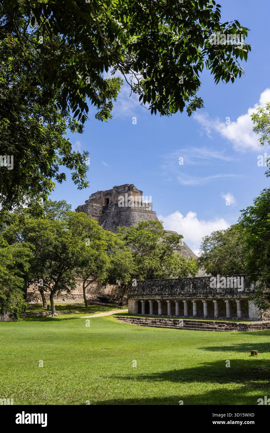 Pyramide des Magiers durch Bäume hinter dem Nonnenkastenviereck in Uxmal, Yucatán, Mexiko. Stockfoto