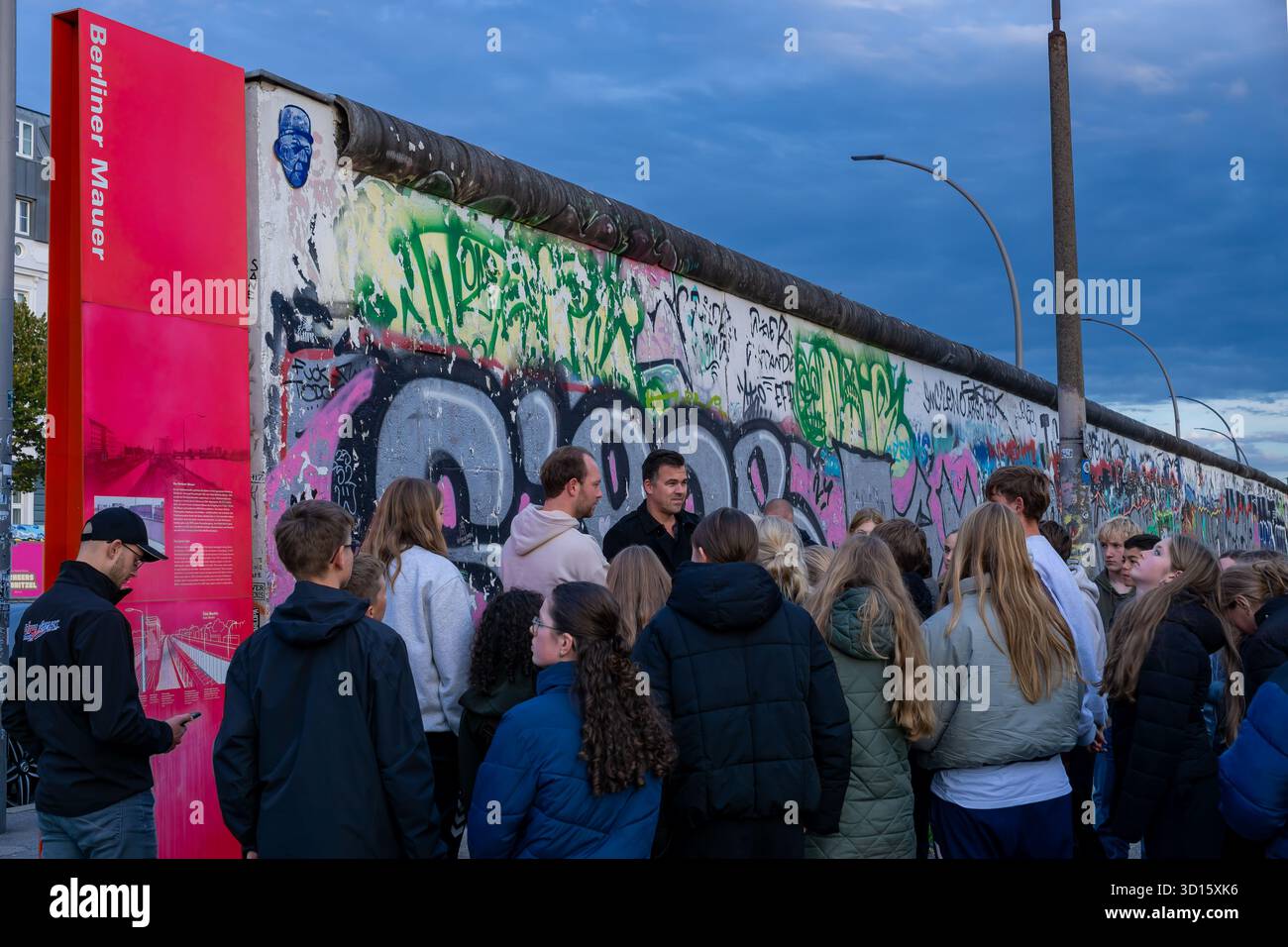 Tourgruppe mit einem Reiseleiter in der Berliner Wall East Side Gallery in Berlin, Deutschland. Stadttourismus, Gruppe von Touristen, Tourgruppe, geführte Tour. Stockfoto