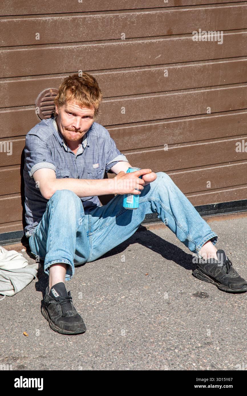 Mann sitzt auf dem Bürgersteig und genießt Getränke beim Kallio Block Party 2025 Street Festival im Bezirk Kallio in Helsinki, Finnland Stockfoto