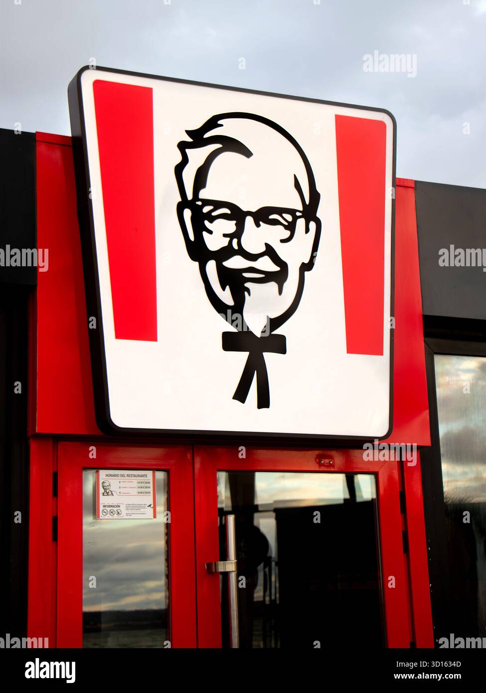 Äußere eines KFC-Fast-Food-Restaurants mit dem legendären Colonel Sanders-Logo über roten Türen Stockfoto