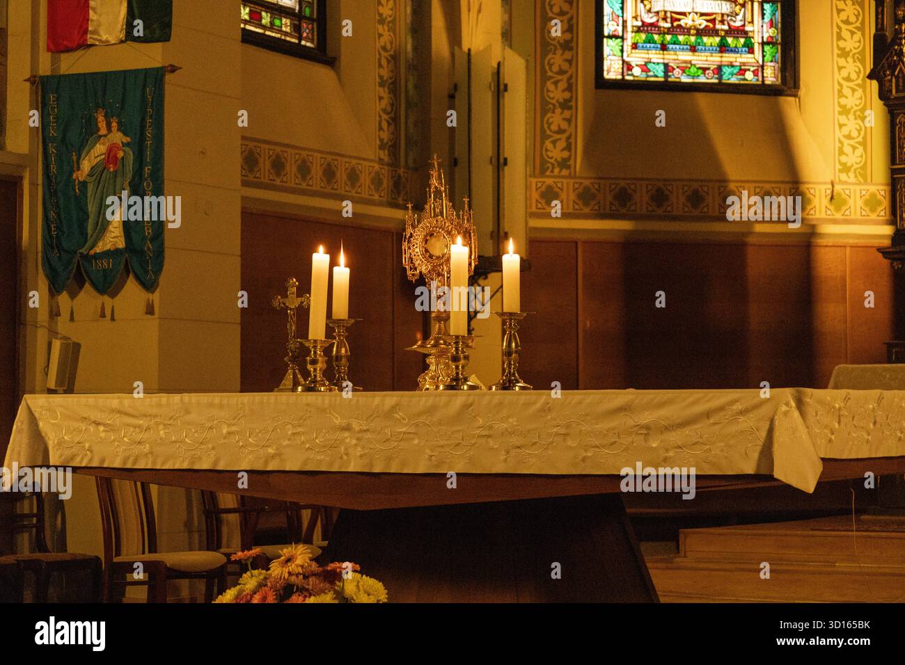 Zündete Kerzen auf dem Kirchenaltar mit goldenem Kelch und Kreuz an Stockfoto