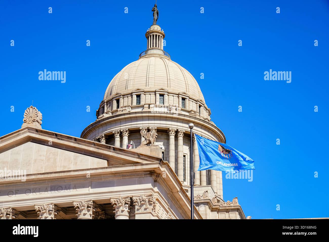 Nahaufnahme der Kuppel des Oklahoma State Capitol unter einem blauen Himmel mit der Landesflagge im Vordergrund Stockfoto