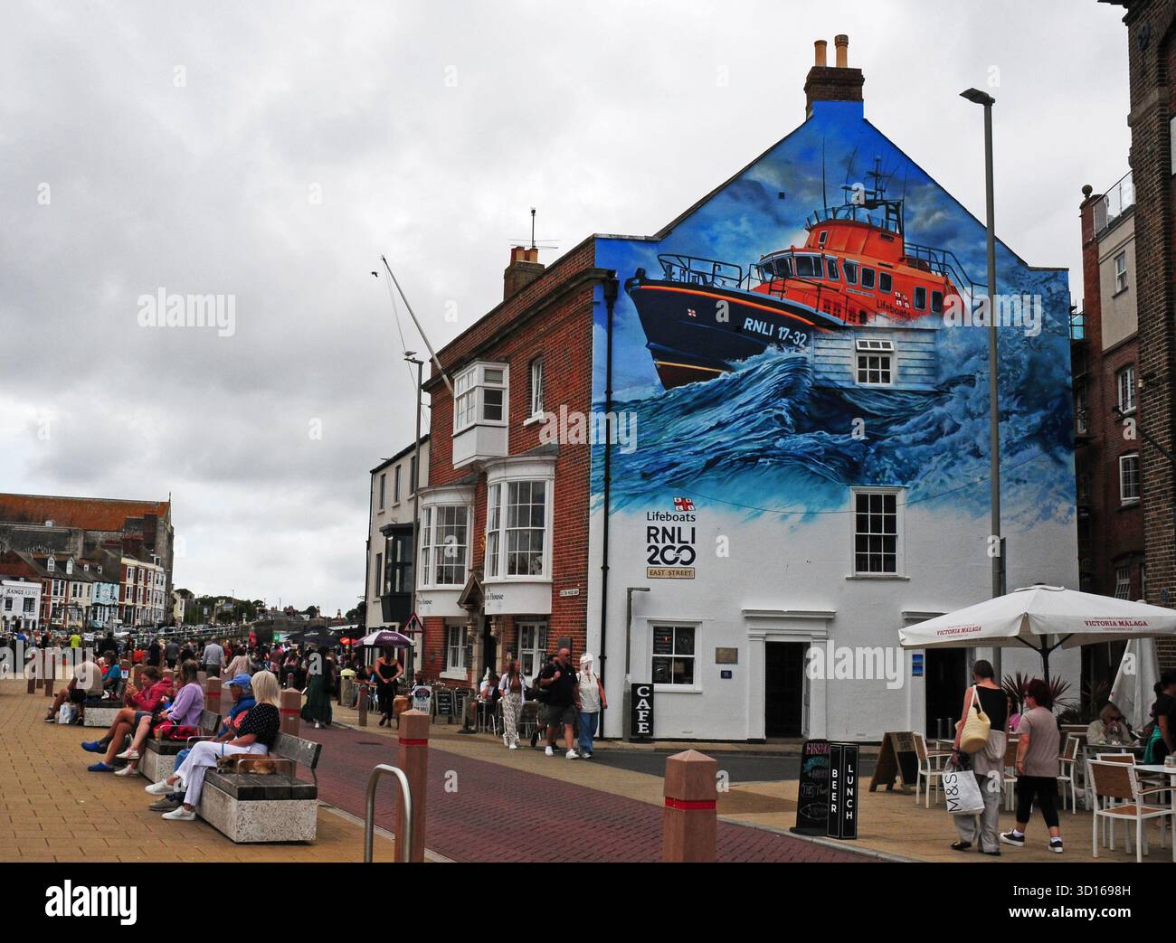 Gemälde, das dem RNLI gewidmet ist, an der Seite eines Gebäudes im Hafen von Weymouth. Stockfoto
