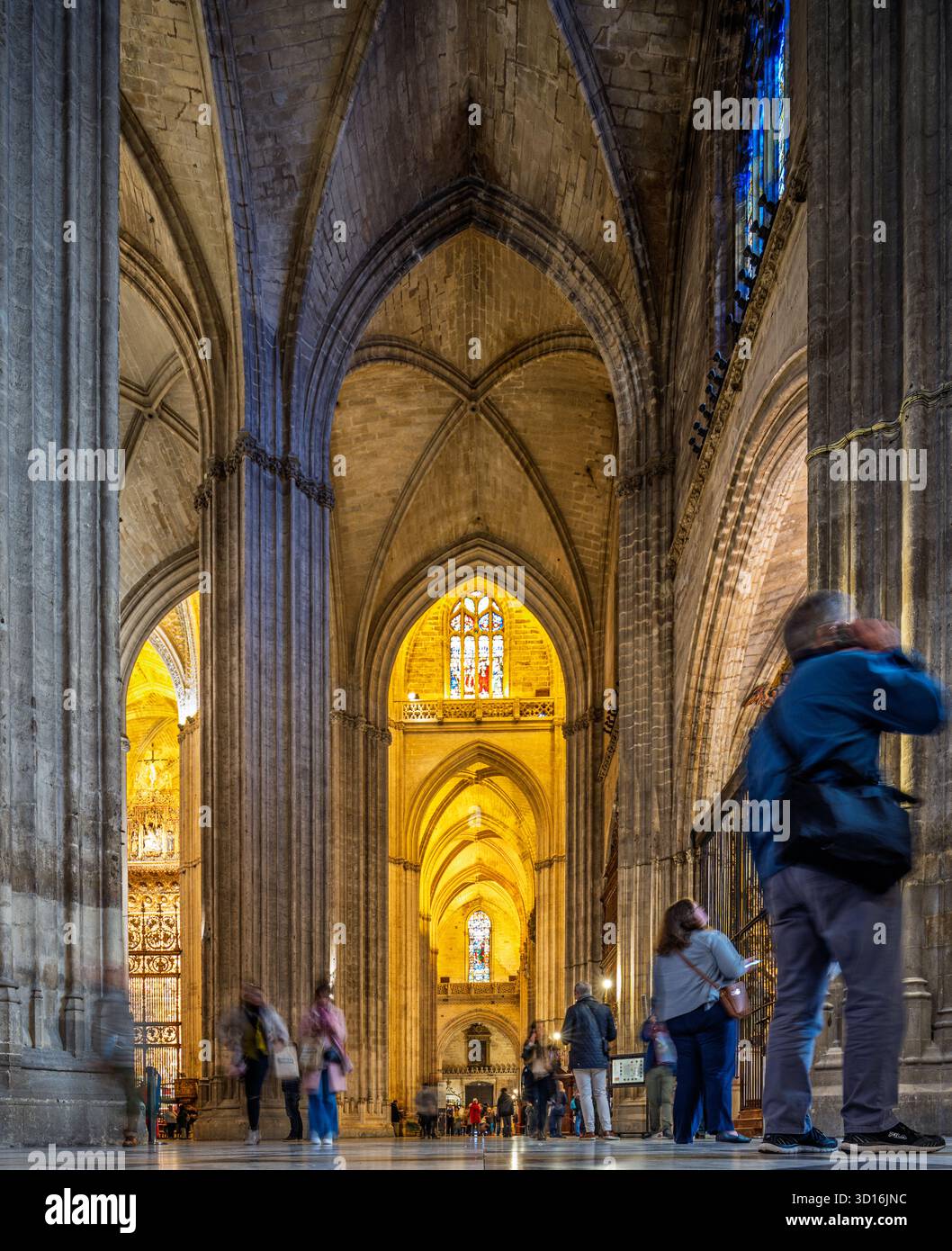 Sevilla, Spanien, 3. Januar 2020, Besucher schlendern durch das Seitenschiff der Kathedrale von Sevilla, umgeben von hoch aufragenden Säulen und gefiltertem Licht, das bea ist Stockfoto