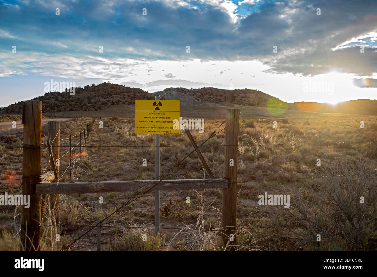Jeffrey City, Wyoming - die Sonne geht hinter einem Schild auf, das den Umkreis einer ehemaligen Uranmine und -Mühle schmückt, die von dort aus betrieben wurde Stockfoto