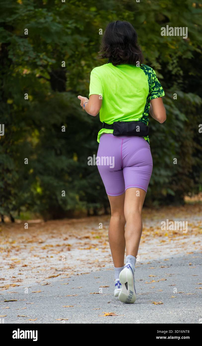 Frau mittleren Alters, die durch den friedlichen Park läuft, in sportlichem Outfit, das sich auf Fitness Gesundheit und Gleichgewicht im aktiven Outdoor-Lifestyle konzentriert. Stockfoto