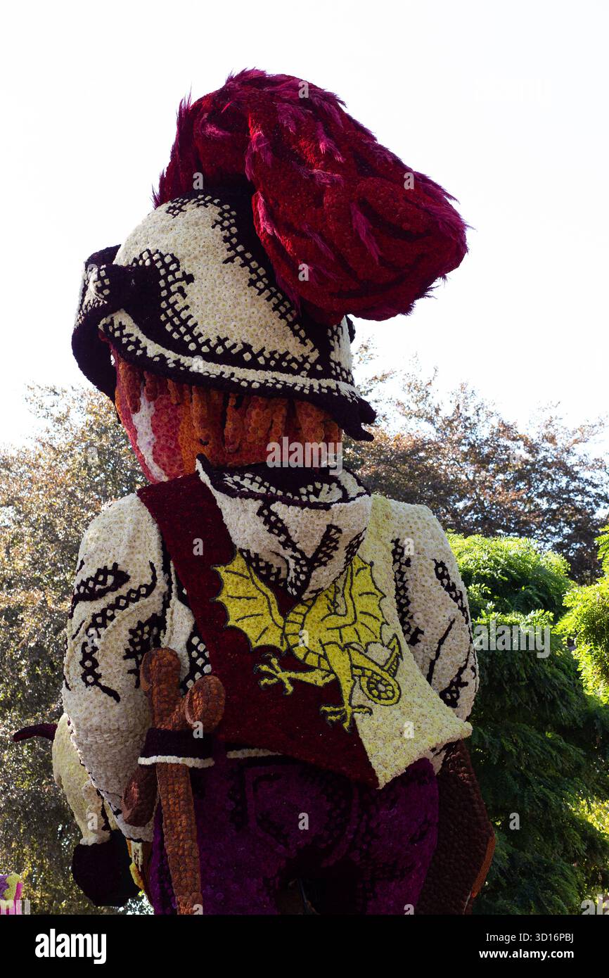 Vertikale dramatische Ansicht der dunkelroten Flottenskulptur mit großen gekrümmten Elementen und dichter Dahlienabdeckung. Stockfoto