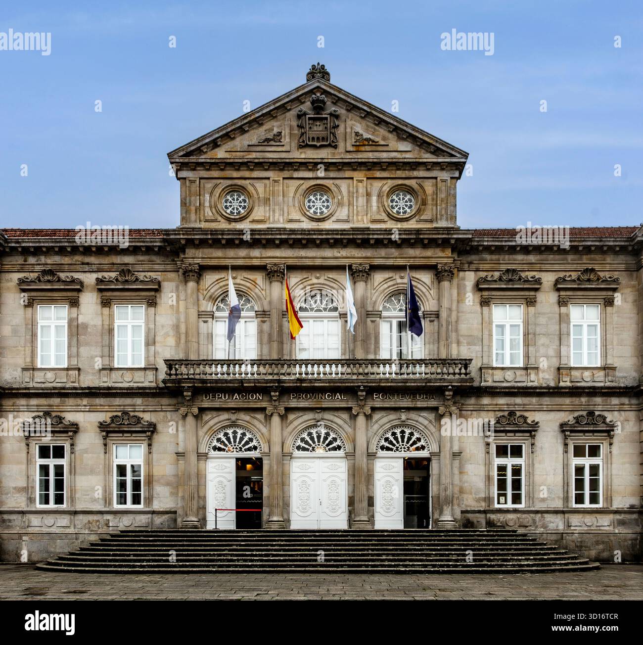 Neoklassizistische Fassade der Deputación Provincial de Pontevedra, Spanien, mit verzierten Mauerwerken, Säulen, Flaggen, und symmetrisches architektonisches Design. Stockfoto