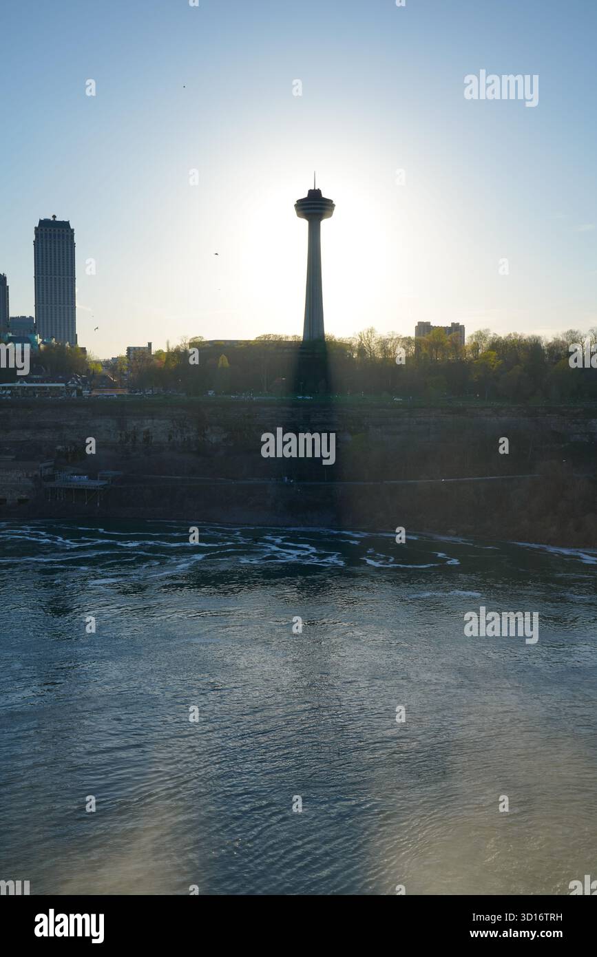 Der Skylon Tower steht vor der untergehenden Sonne, während Licht über den Niagara River fließt, der von der amerikanischen Seite erfasst wurde Stockfoto