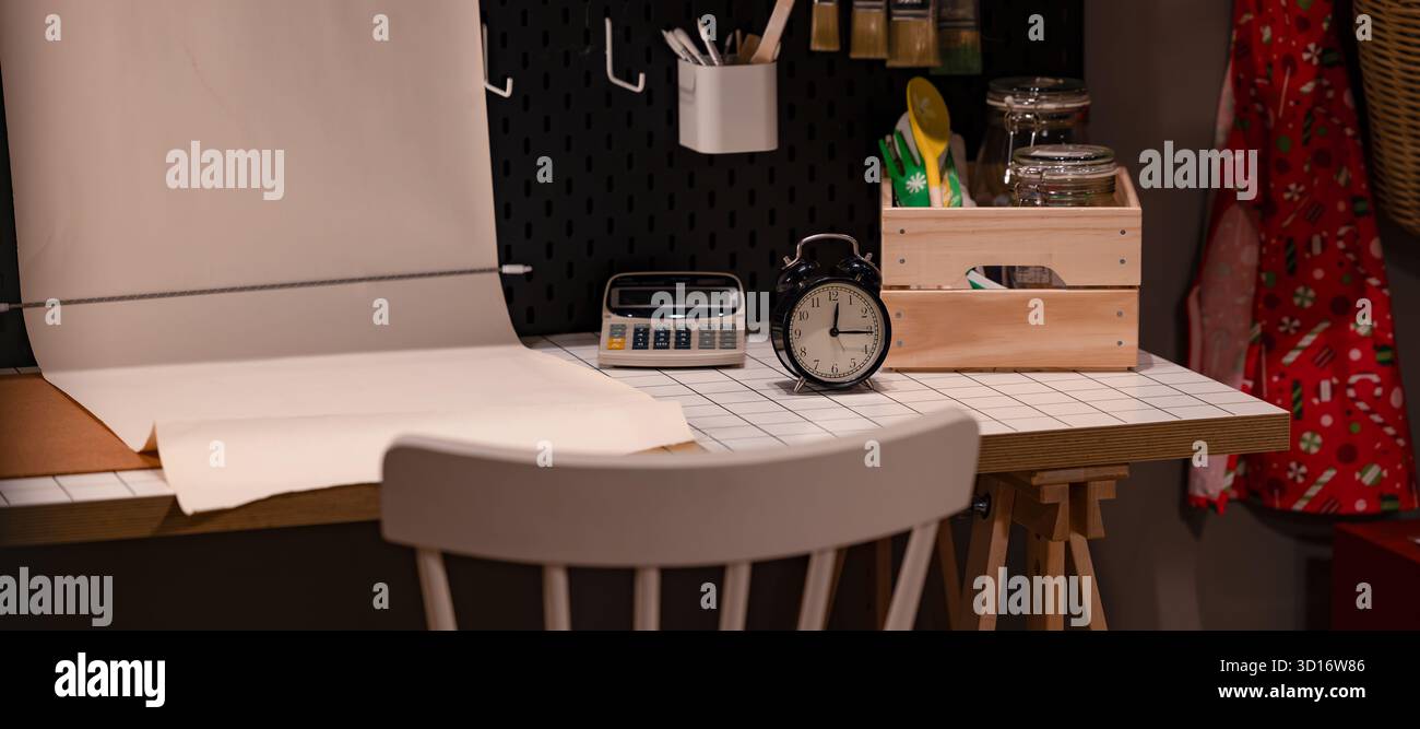 Minimalistische Einrichtung des Heimbüro-Schreibtisches mit Wecker-Rechner und Papierkorrektur auf weißem Tisch Stockfoto