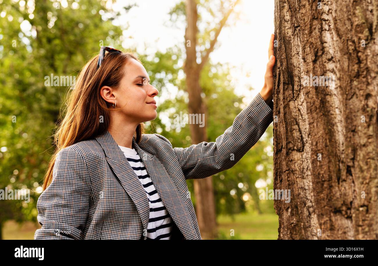 Achtsame Stadträtin berührt den Baum und verbindet sich mit der Natur im Freien Stockfoto