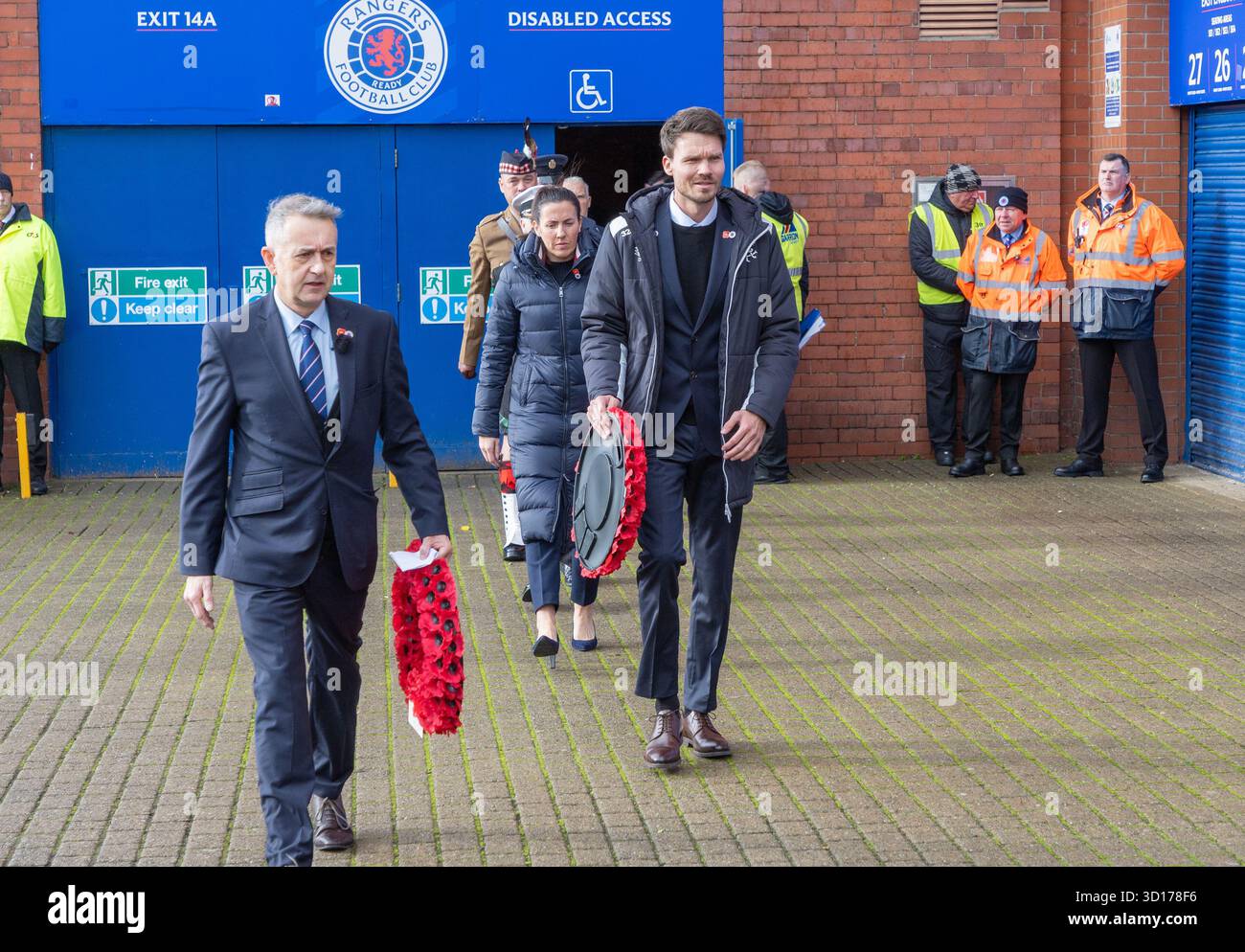 Glasgow, Schottland, Großbritannien. Oktober 2025. Glasgow, Großbritannien. Als Zeichen des Respekts und der Tradition legten Vertreter des Rangers FC, darunter Danny Rohl, der Cheftrainer, Kränze am Fuße der Statue von John Greig, einem berühmten Rangers-Spieler. Es ist üblich, dass die Zeremonie am Tag eines Heimspiels vor und am nächsten 11. November stattfindet. Bei dieser Gelegenheit wurde das Spiel gegen Kilmarnock FC ausgetragen und Vertreter von Kilmarnock, darunter Stuart Kettlewell, Kilmarnocks Trainer, legten einen Kranz. Die Zeremonie unterstützte die Wohltätigkeitsorganisation „Combat to Coffee“. Quelle: Findlay/Alamy Live News Stockfoto