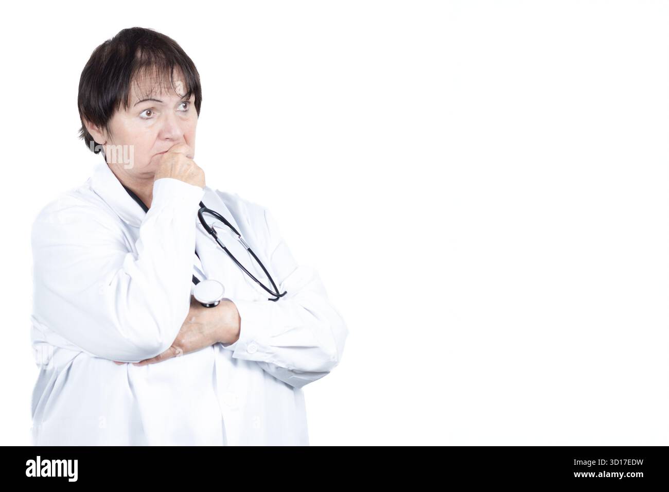 Reife Frau Ärztin trägt einen weißen Labormantel und Stethoskop, sieht nachdenklich und nachdenklich aus, während sie eine komplexe medizinische Herausforderung in Betracht zieht Stockfoto