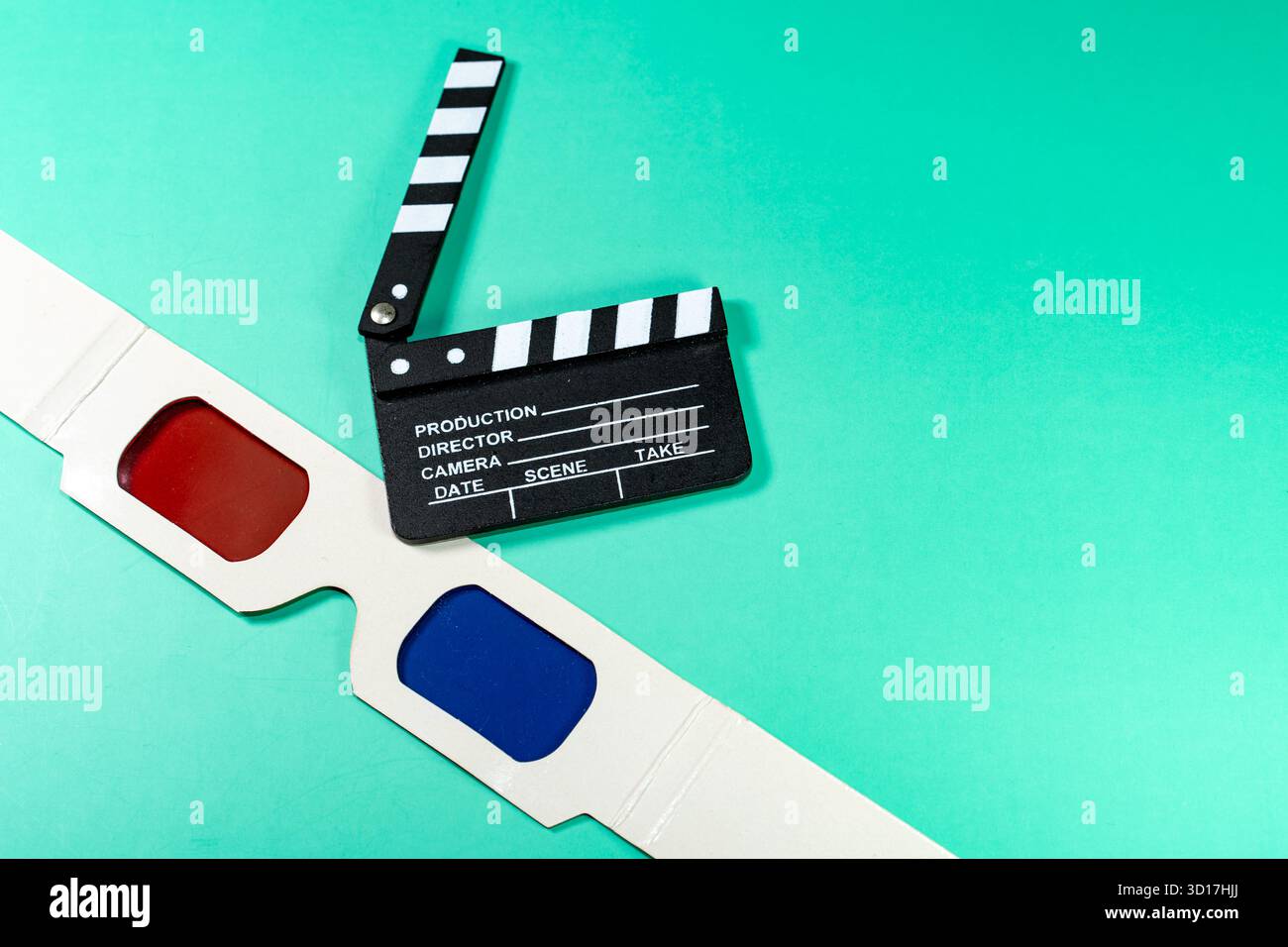 Eine Kinokomposition mit Wandtafel und 3D-Brille vor leuchtendem, blauem Hintergrund, perfekt für Film- und Kinothemen. Stockfoto