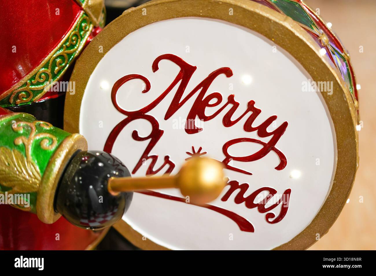 Farbenfrohe Spielzeugtrommel und festliche Einrichtung mit Merry Christmas-Schild – perfekt für warme, nostalgische Weihnachtsbilder und saisonale Themen. Stockfoto
